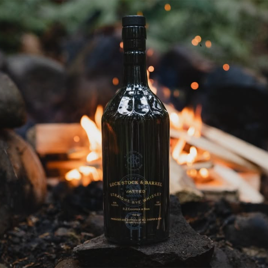 Lock Stock & Barrel Vatted Straight Rye Whiskey bottle in front of a campfire.