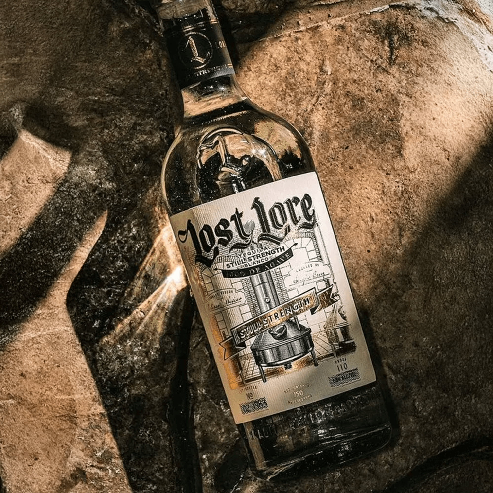 Lost Lore Still Strength Blanco Tequila bottle displayed on textured surface, showcasing its artisanal design and bold spirit.