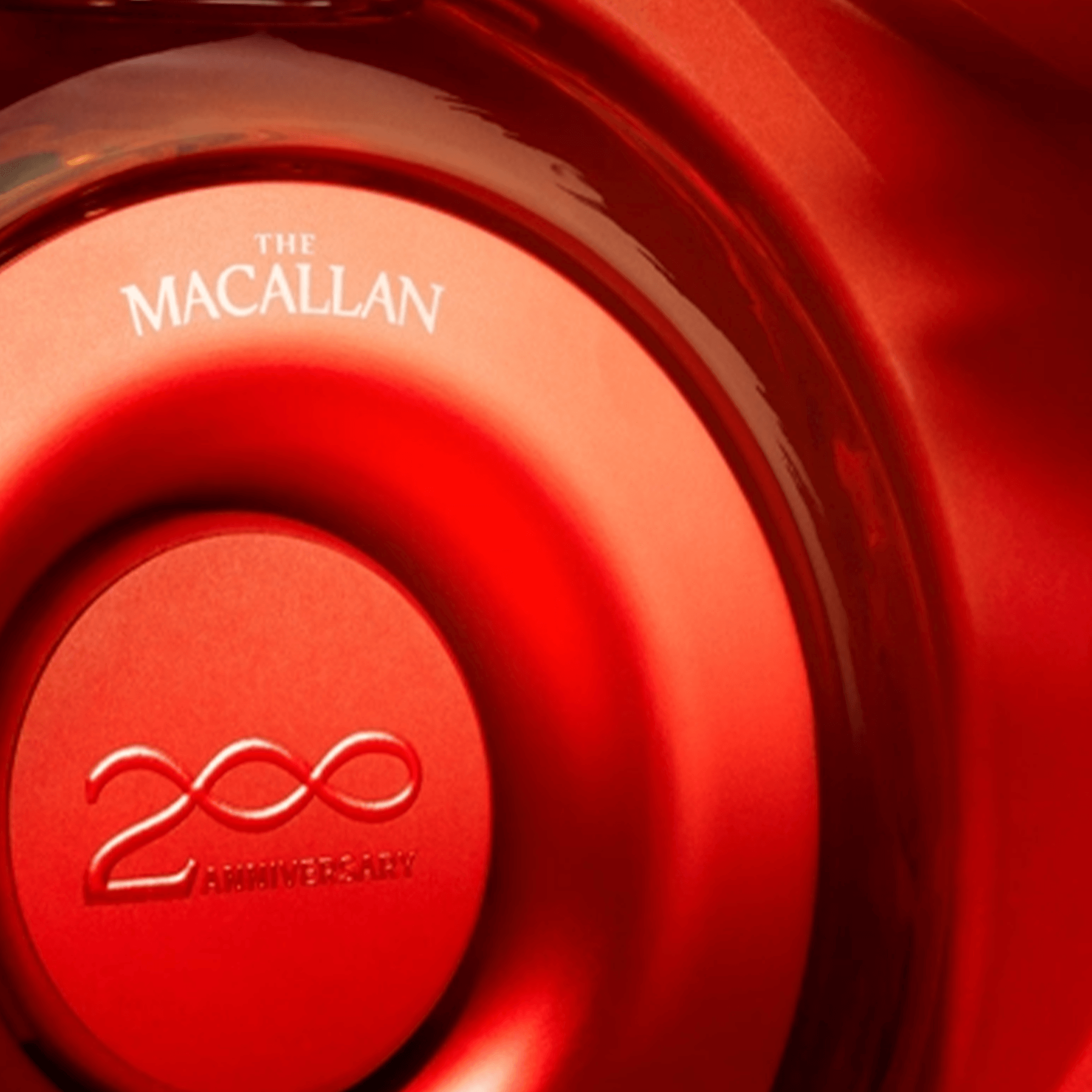 Close-up of The Macallan whisky bottle showcasing 200th anniversary emblem in a striking red design.