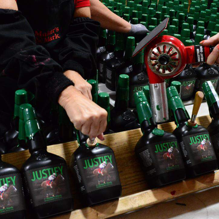 Bottles of Maker's Mark Justify bourbon 2018 being sealed in a distillery during production.