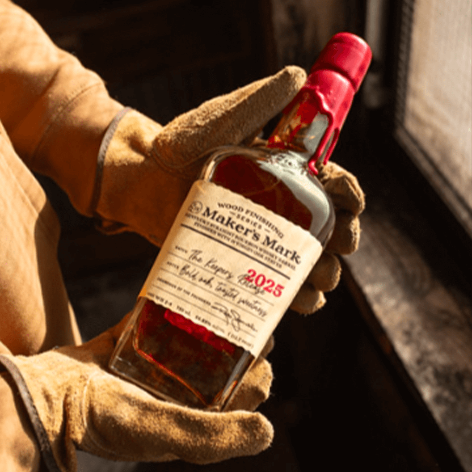 Maker's Mark The Keepers Release 2025 Bourbon bottle held in gloved hands, showcasing craftsmanship and rich flavors.