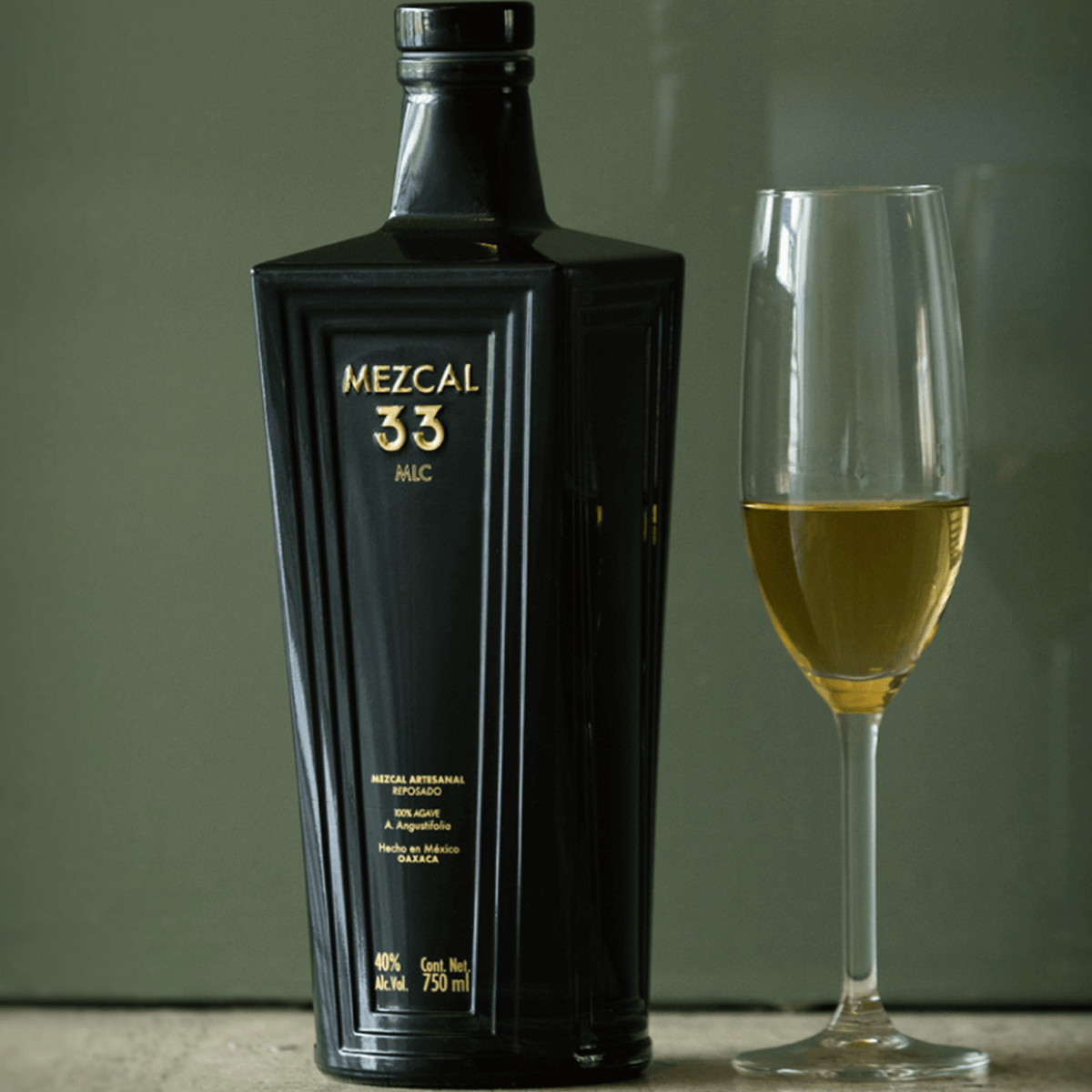 Mezcal 33 Reposado Espadin bottle with a glass, showcasing its rich golden color and sophisticated design.