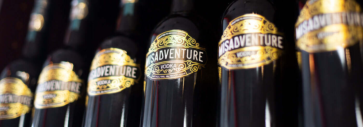 Row of Misadventure Sustainable Vodka bottles featuring elegant label design and branding.