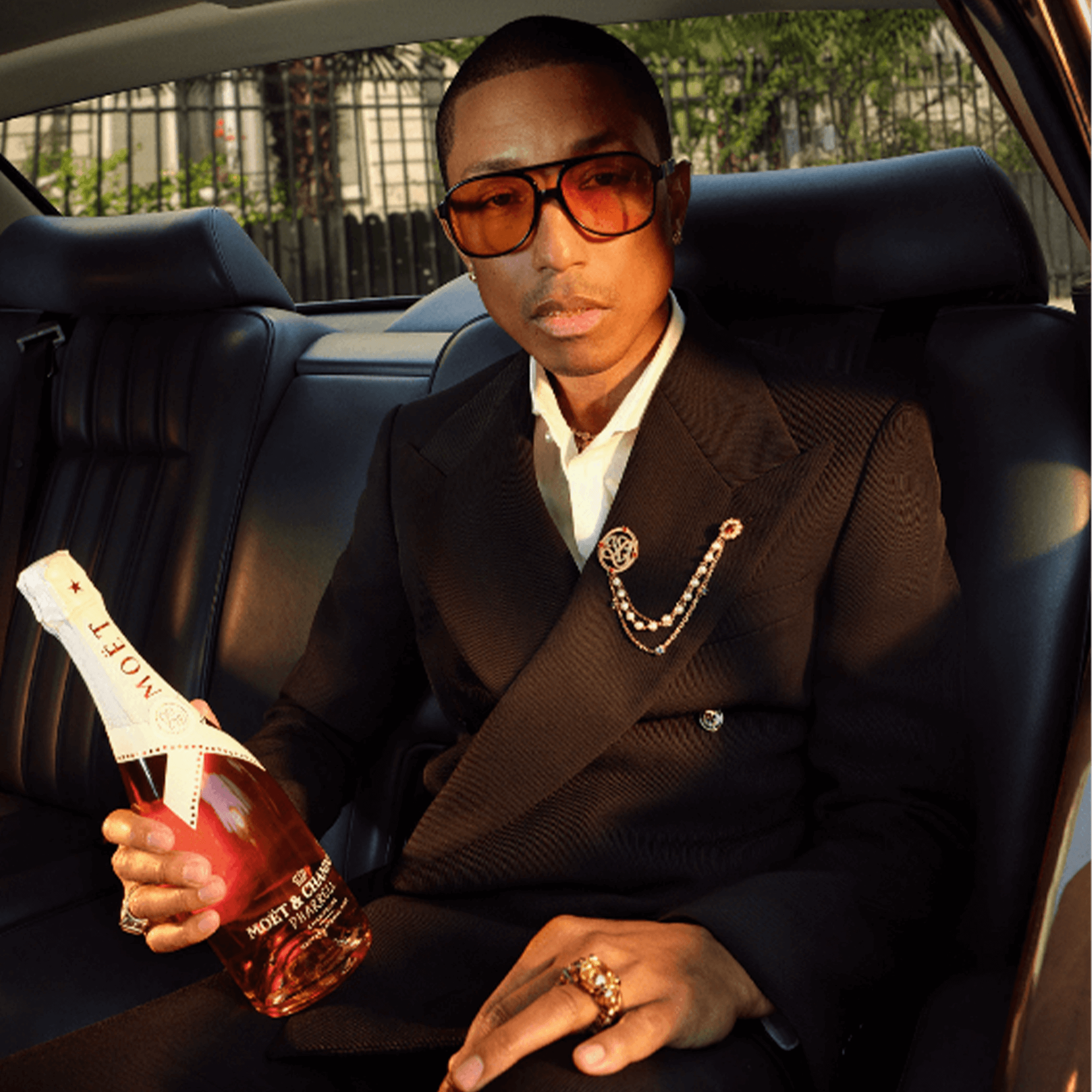 Pharrell Williams holding Moët & Chandon Nectar Impérial Rosé in an elegant car interior, showcasing limited edition design.