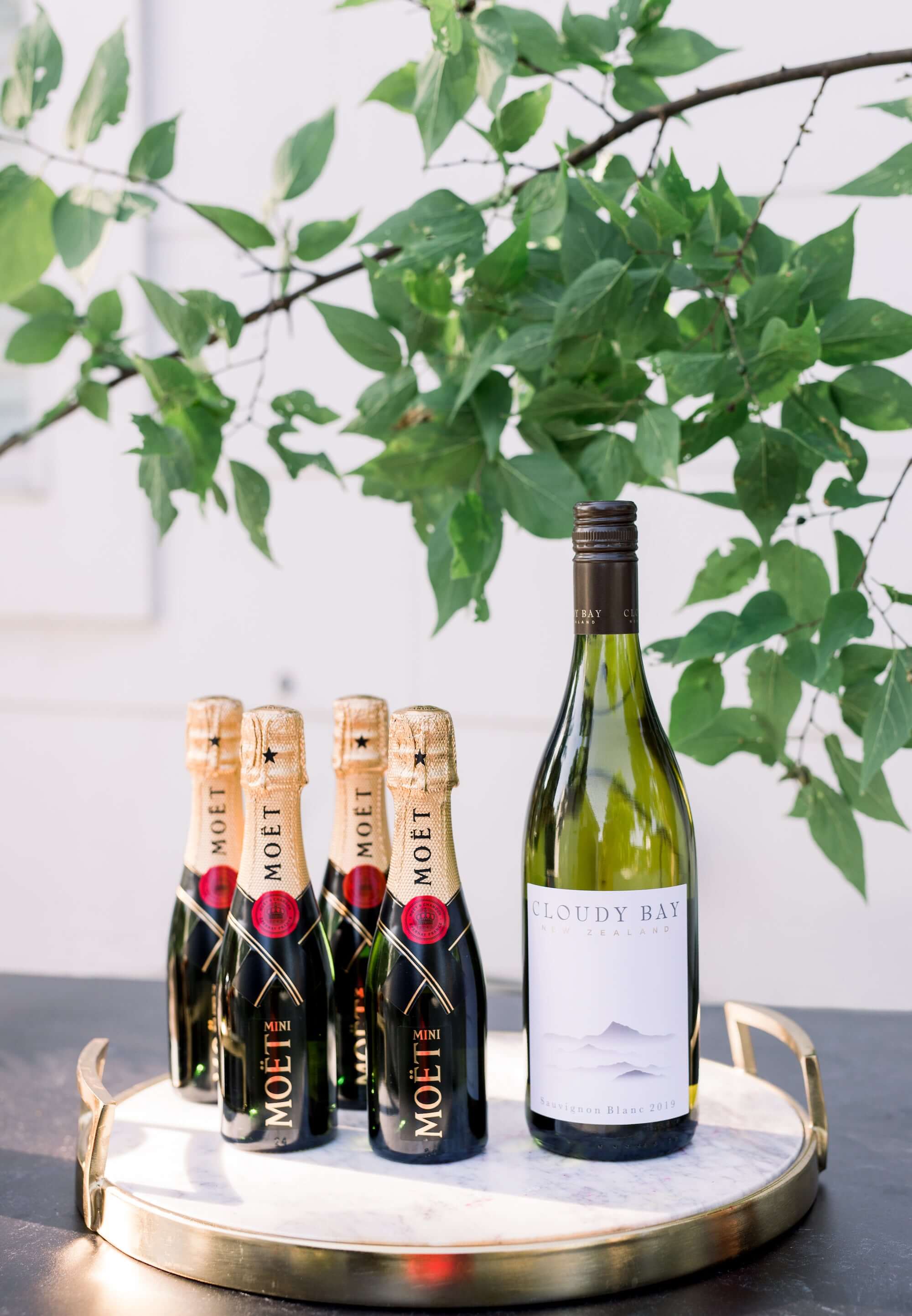 Moët & Chandon Brut Impérial champagne bottles alongside Cloudy Bay wine on a decorative tray with greenery.