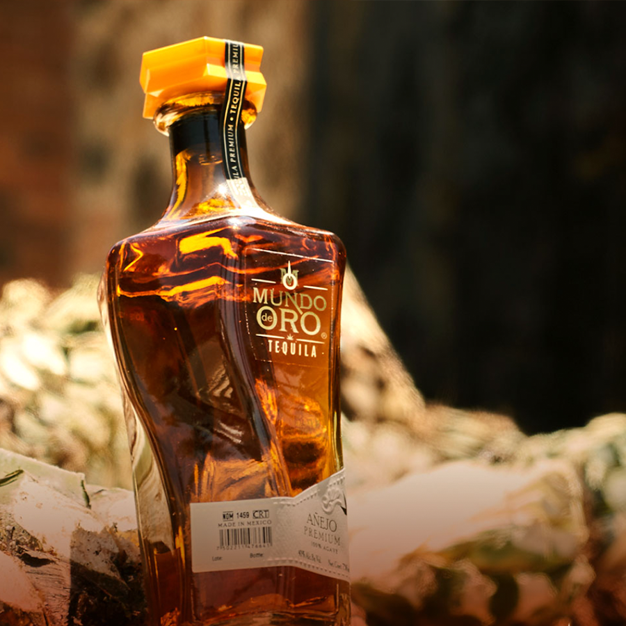 Mundo De Oro Añejo tequila bottle showcasing its rich color and elegant design.