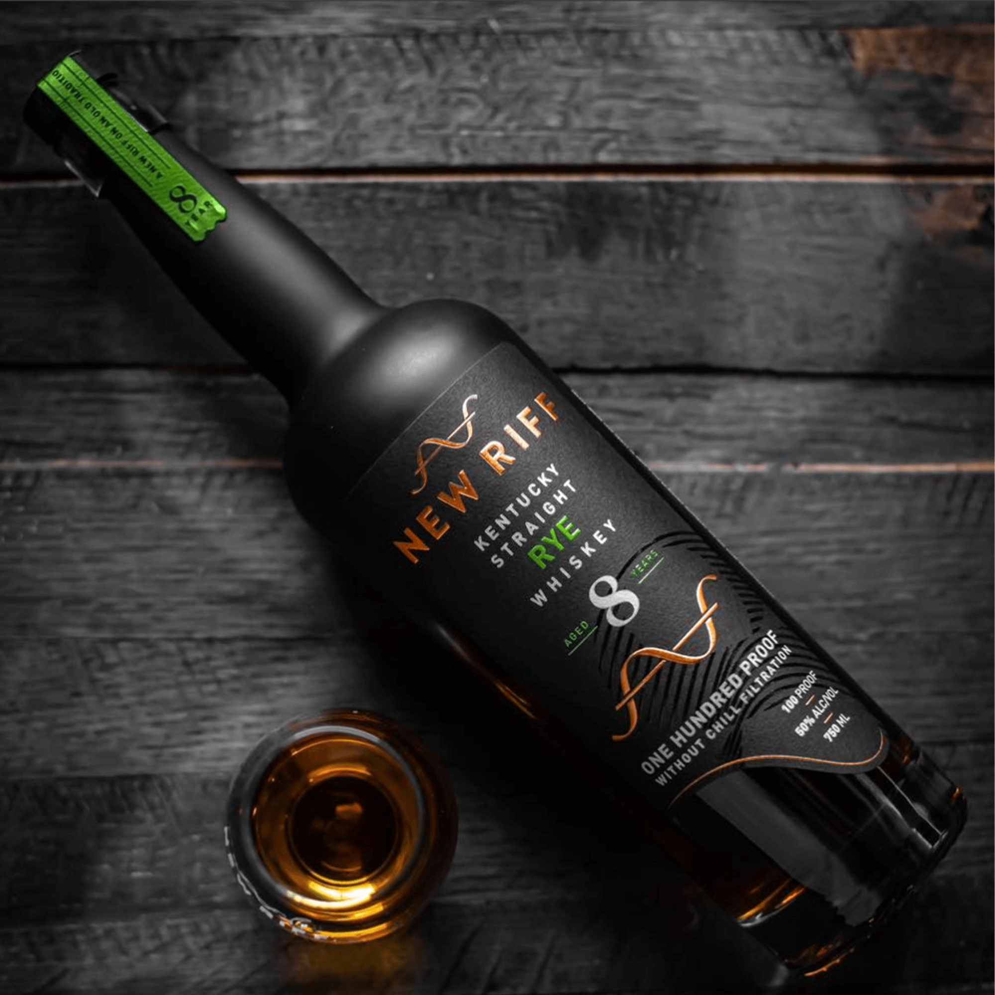 New Riff 8 Year Rye Whiskey bottle with a glass of whiskey on a wooden surface, showcasing rich color and design.
