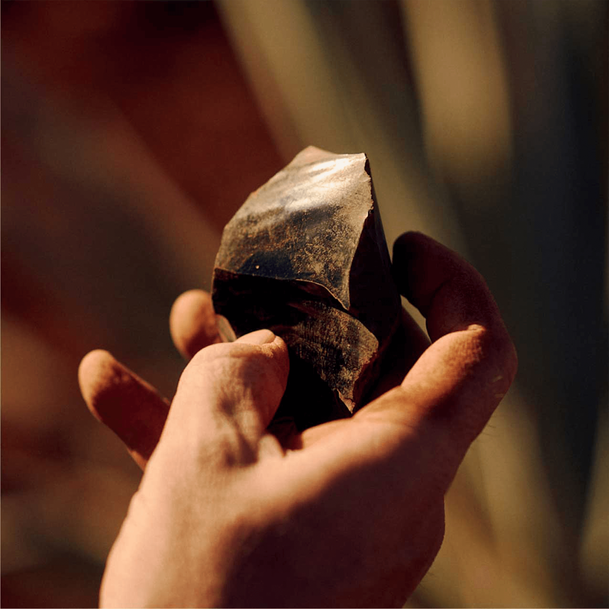 Hand holding a shiny piece of obsidian, a volcanic stone used in crafting Casa Obsidiana Añejo Tequila.