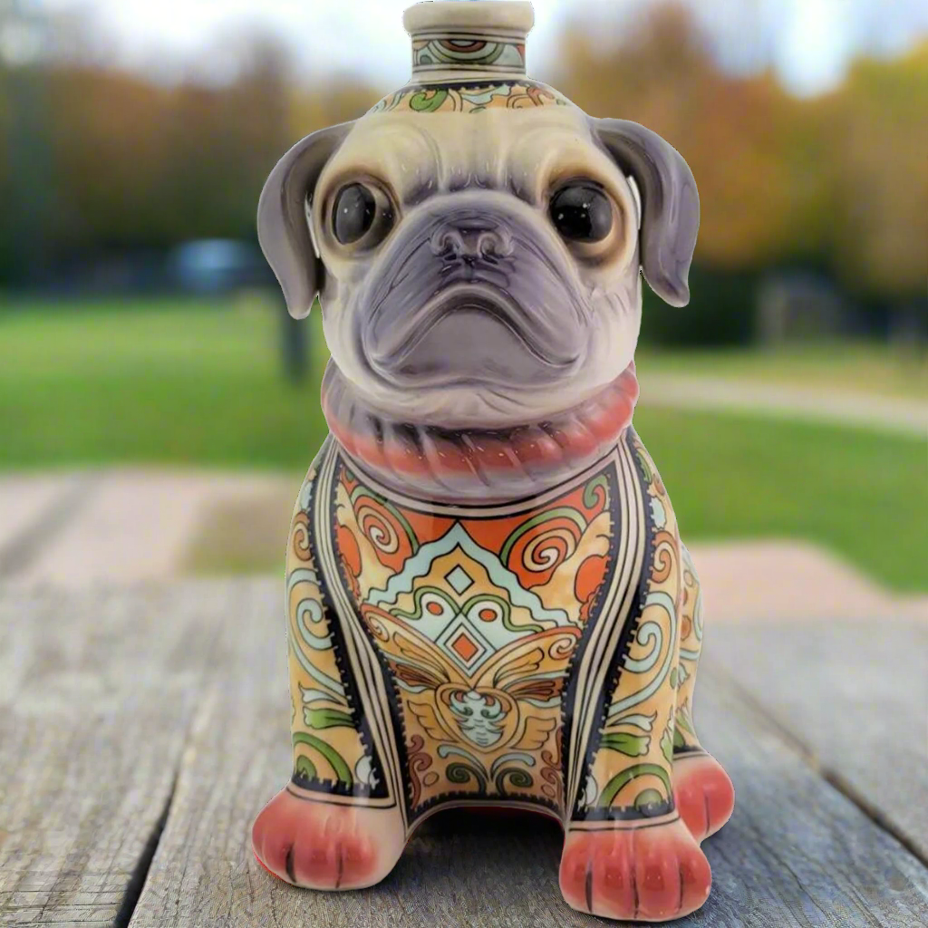 Oceano Azul Añejo Mr Pug Red Tequila bottle designed as a colorful pug, set on a wooden table outdoors.