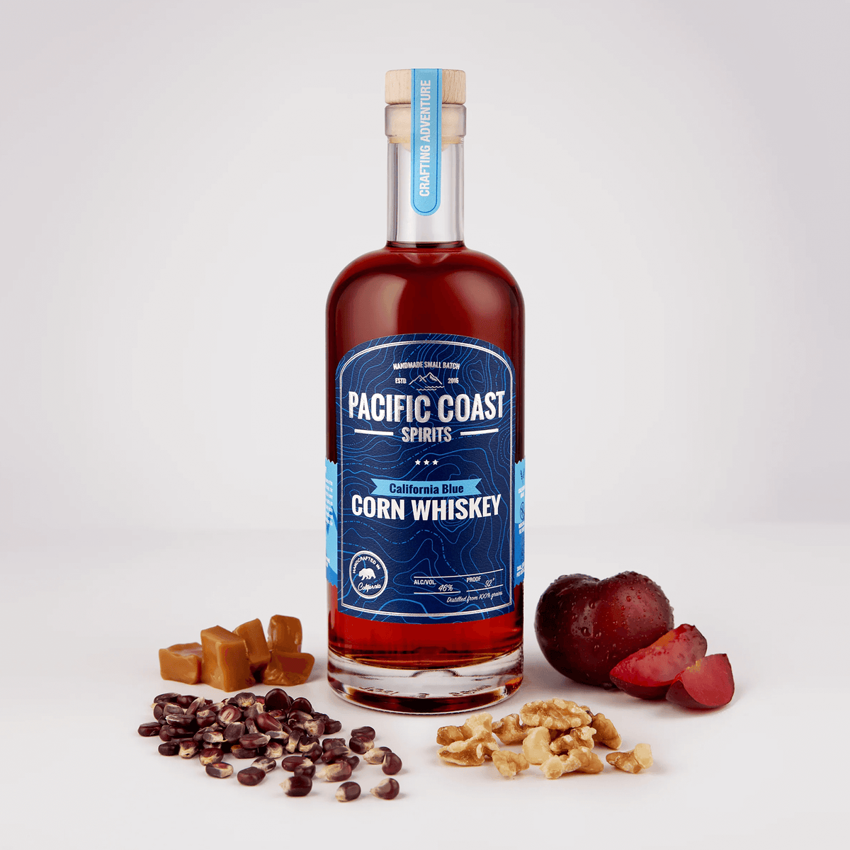 Bottle of Pacific Coast California Blue Corn Whiskey with ingredients like walnuts, plums, and caramel pieces.