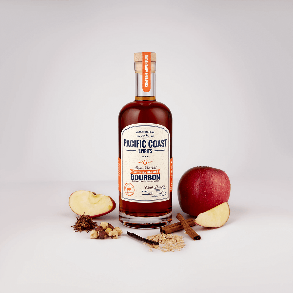 Pacific Coast Wheated Bourbon Single Pot Still 6 Year surrounded by apples, spices, and grains against a neutral background.