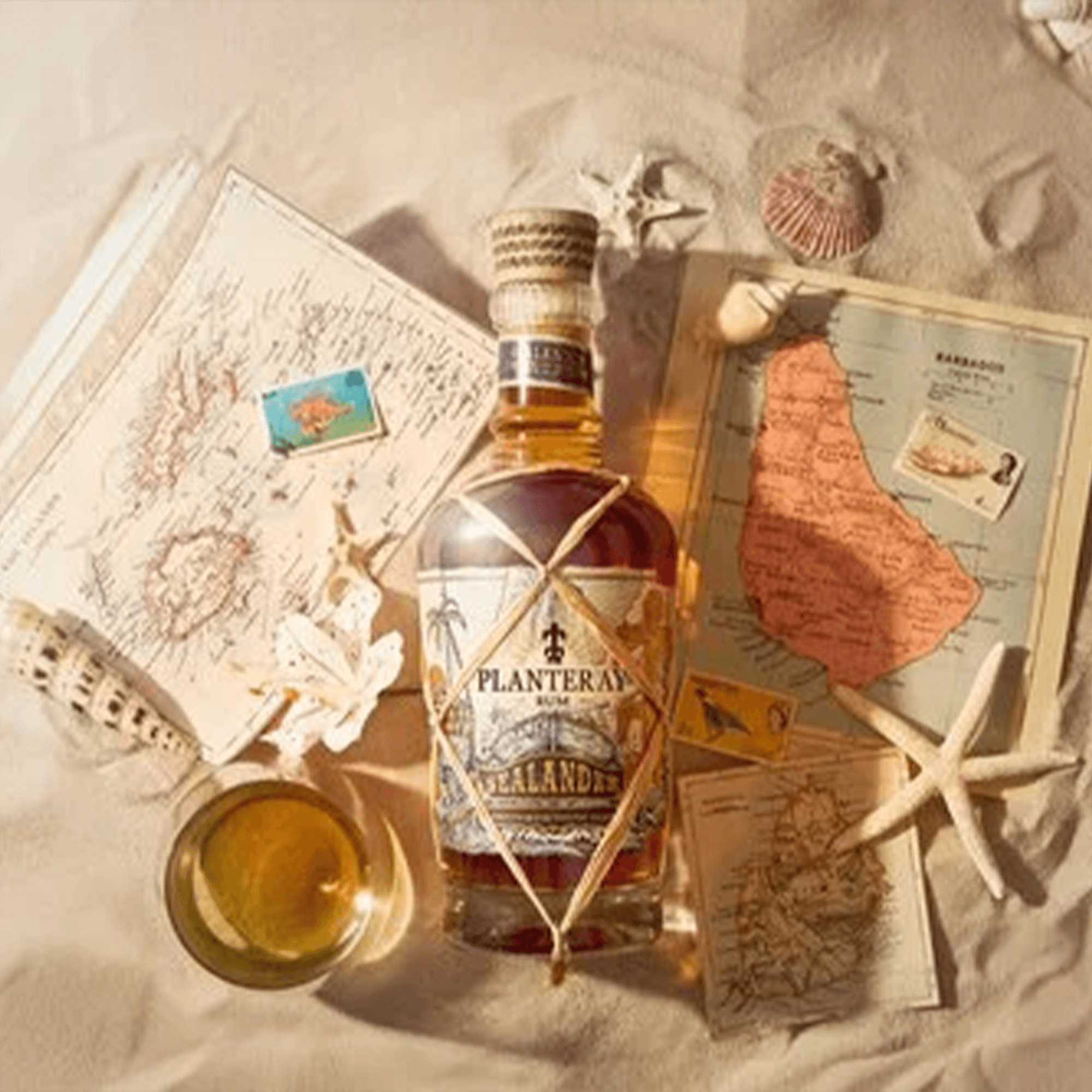 Planteray Sealander Rum 700ml bottle surrounded by maps and seashells on sandy background.
