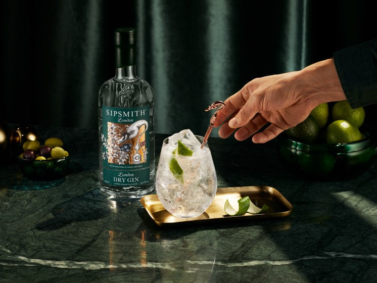 A refreshing Sipsmith London Dry Gin cocktail with lime garnish, set beside the gin bottle on a stylish tray.