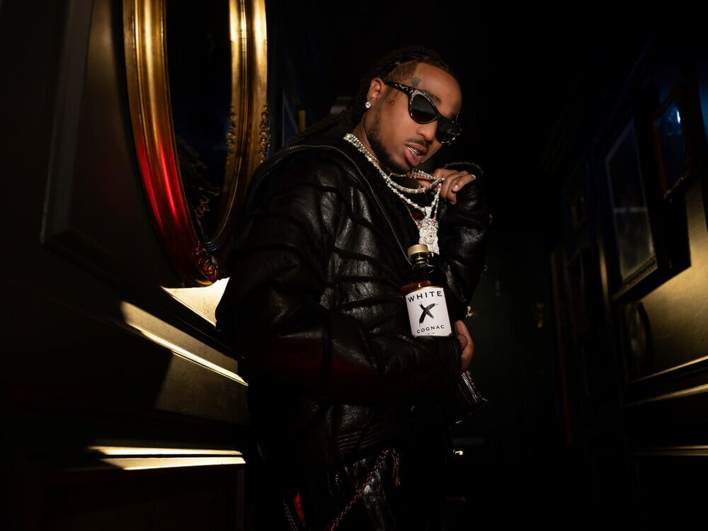 Artist Quavo showcasing White X Cognac in a stylish black outfit, emphasizing modern luxury and artwork.
