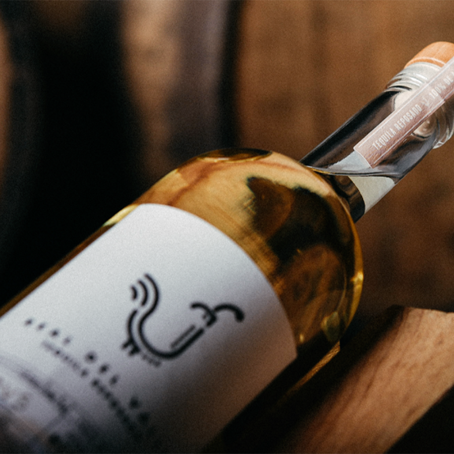 Close-up of Real Del Valle Reposado Tequila bottle showcasing the label and cork against a wooden background.