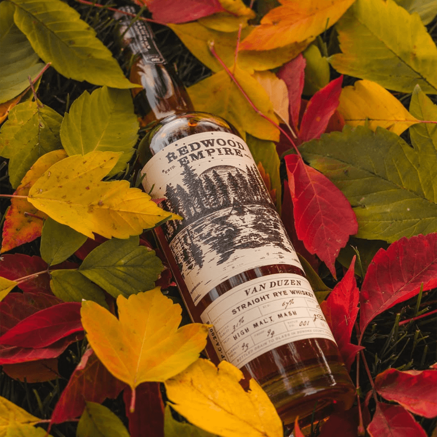 Redwood Empire Van Duzen Straight Rye whiskey bottle surrounded by colorful autumn leaves.