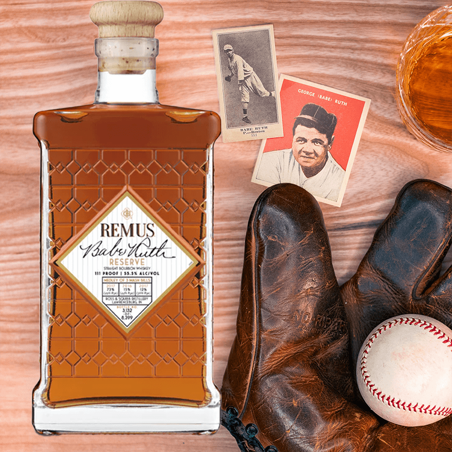 Remus Babe Ruth Reserve Bourbon bottle, baseball glove, Babe Ruth cards, and baseball on wooden table.