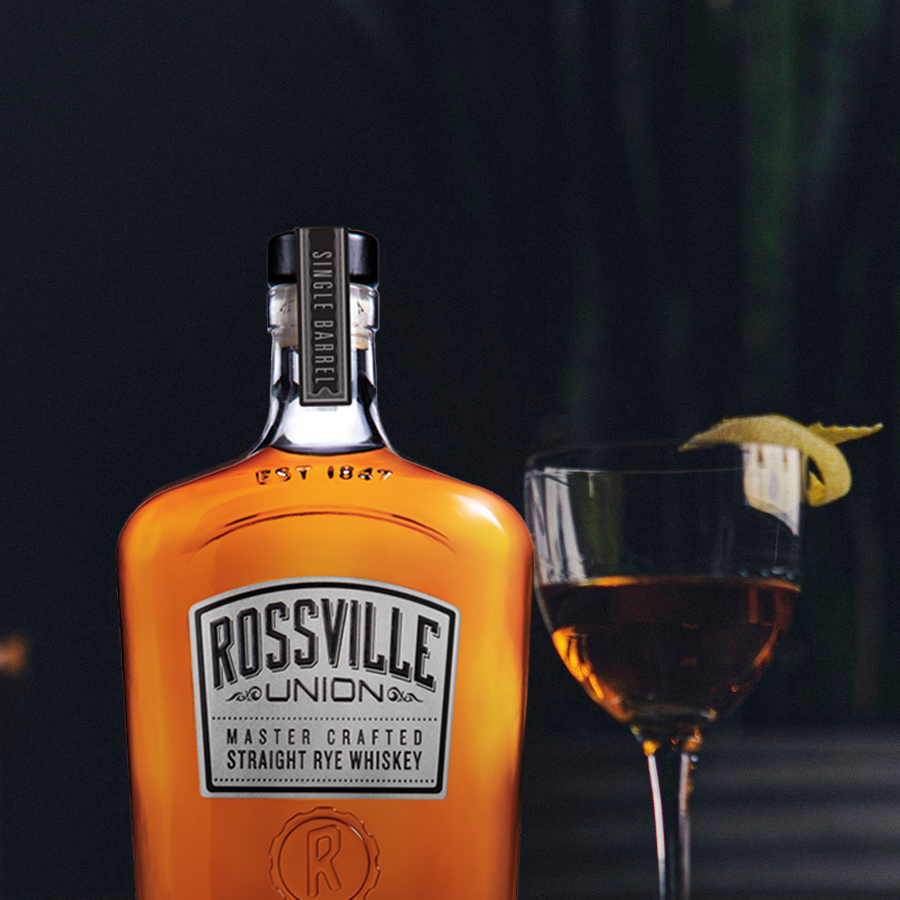 Rossville Union Whiskey bottle standing beside a cocktail glass with a twist, showcasing the rich amber hue.