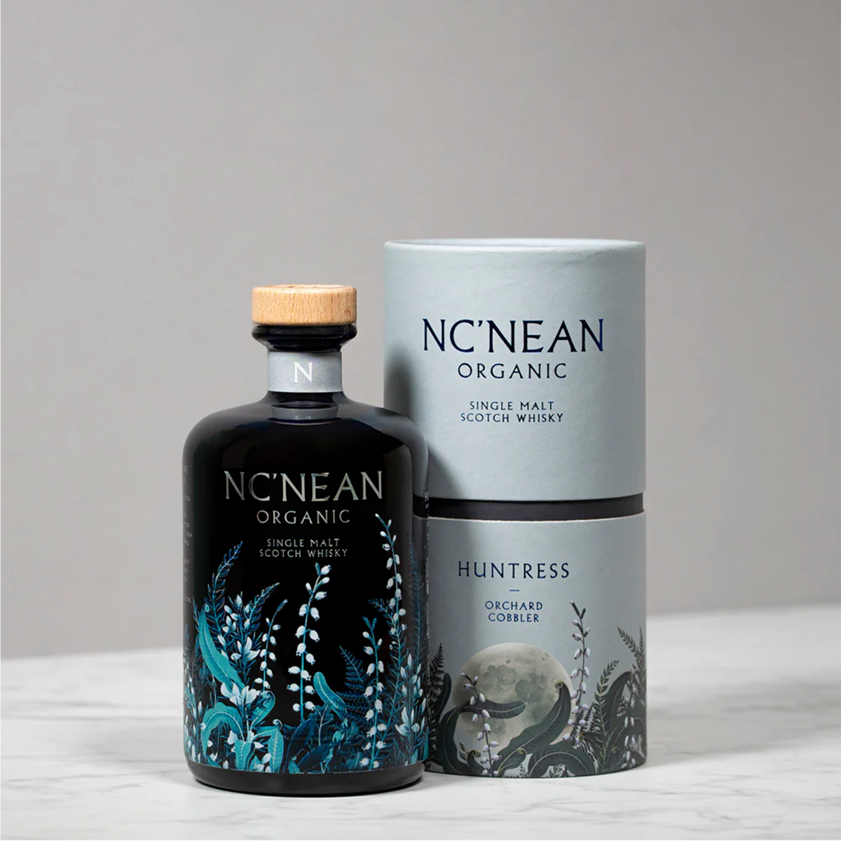 NC'Nean Huntress Orchard Cobbler Organic Single Malt Scotch whisky bottle and packaging on marble surface.