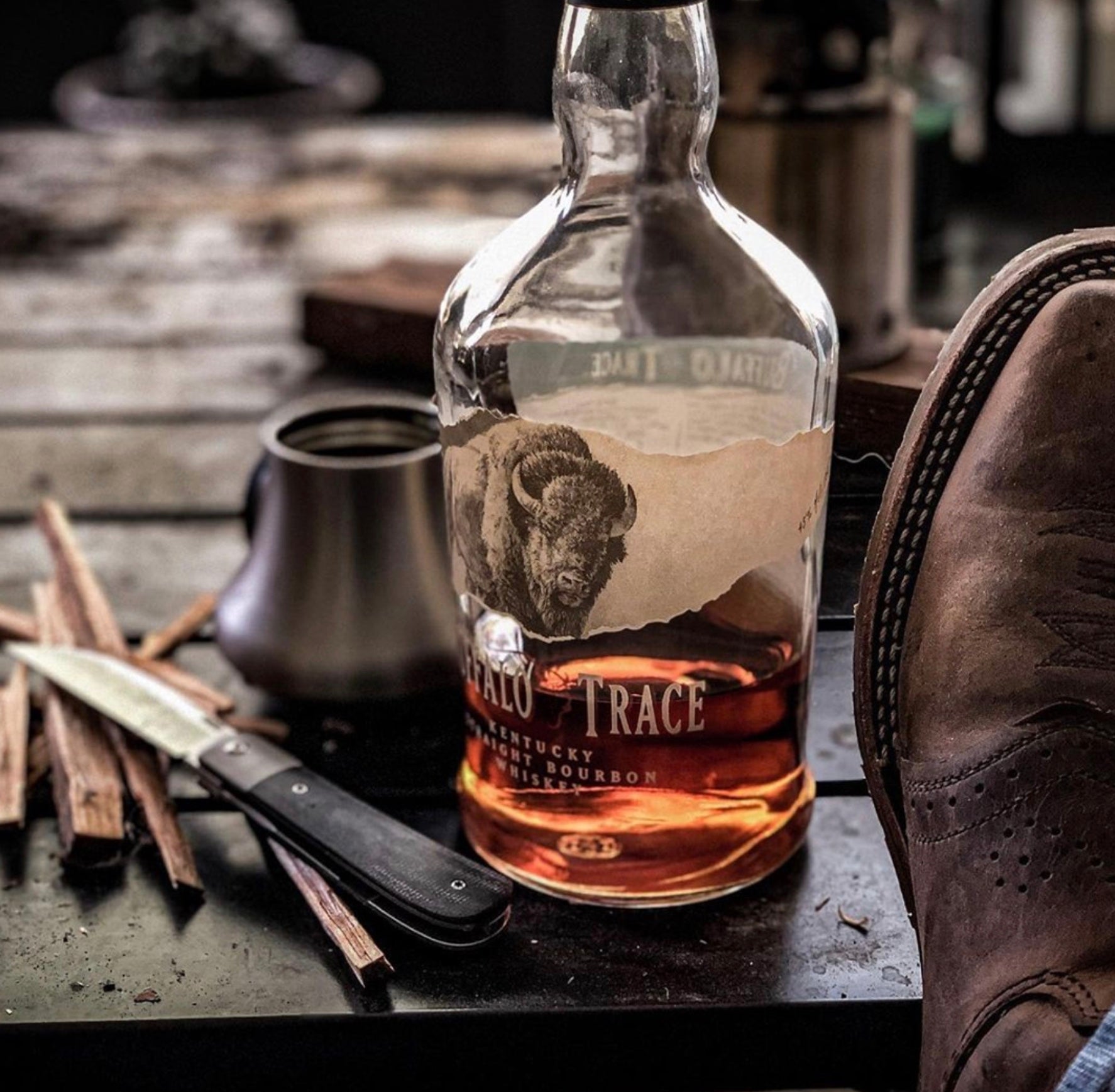 Buffalo Trace Kentucky Straight Bourbon bottle with knife and wooden sticks, showcasing rich amber whiskey color.