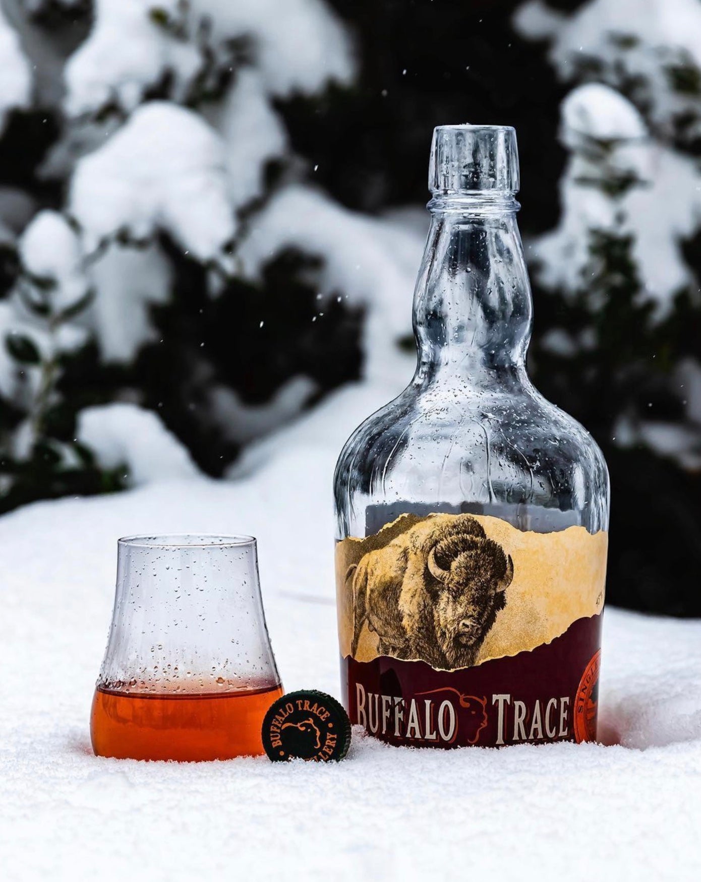 Buffalo Trace Kentucky Straight Bourbon bottle with a glass, set against a snowy backdrop.