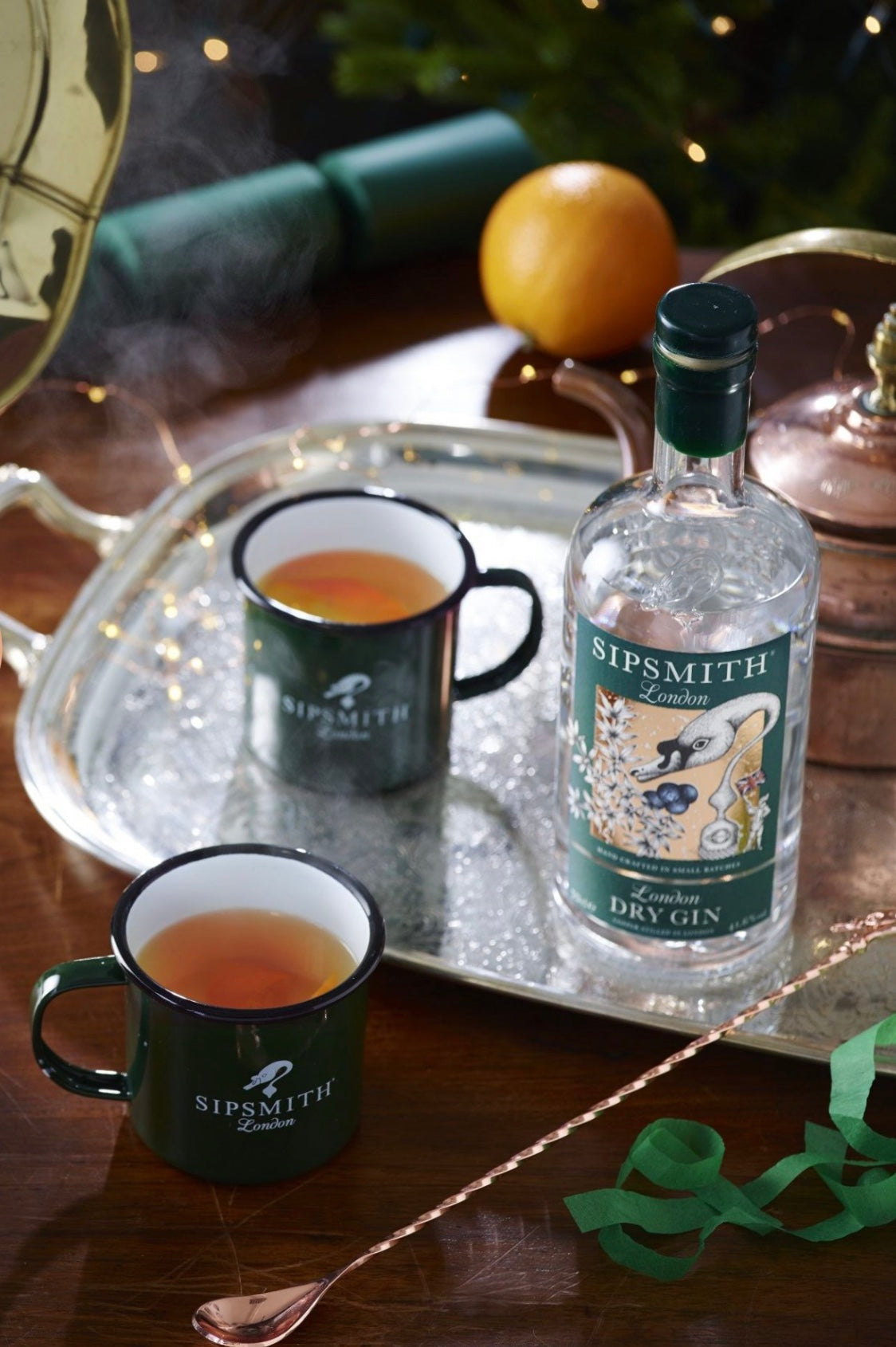 Sipsmith London Dry Gin bottle with two mugs of gin cocktails on an elegant tray, festive background.