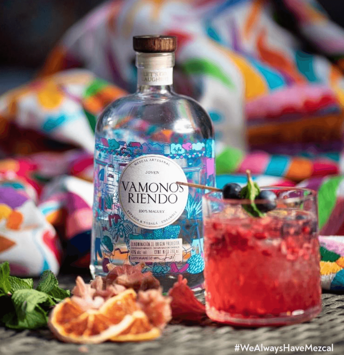 Vamonos Riendo Joven Mezcal bottle with cocktail, showcasing vibrant colors and fresh ingredients.