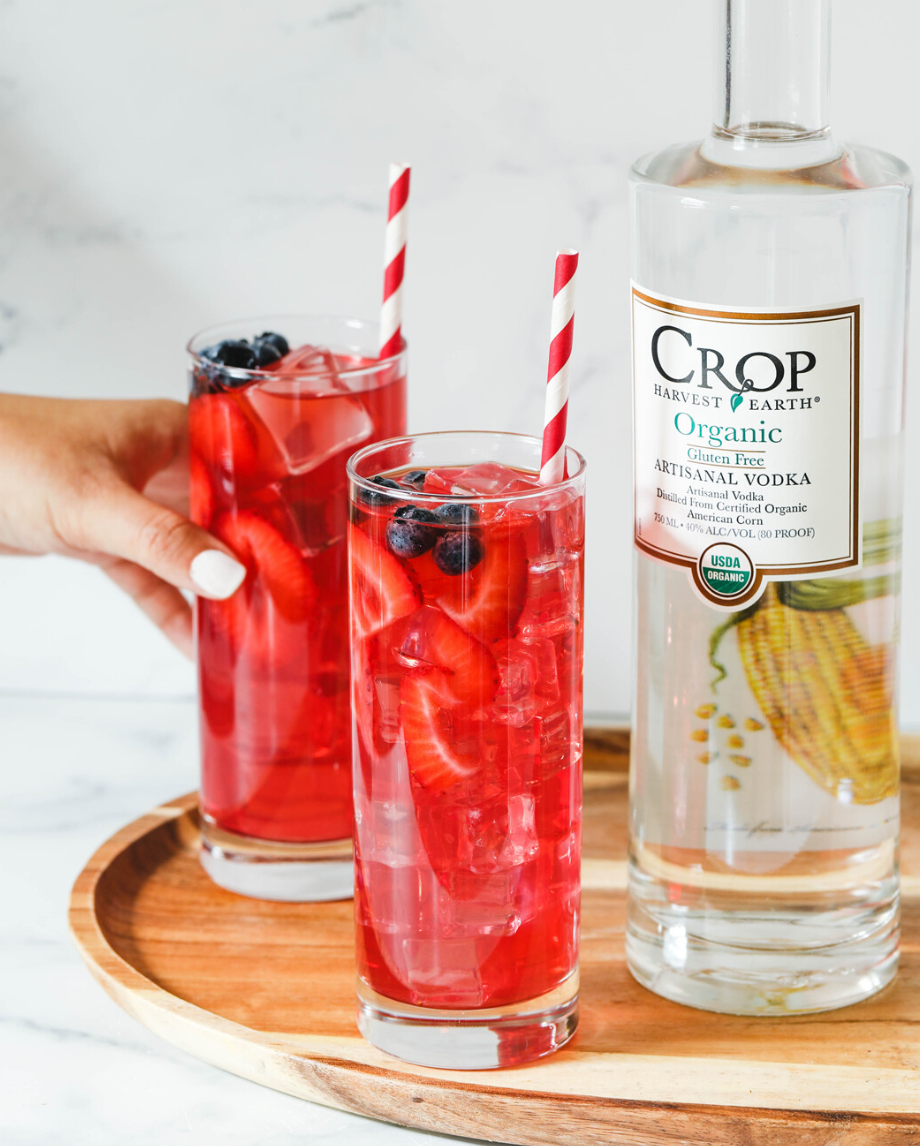 Two colorful cocktails made with Crop Organic Vodka, garnished with strawberries and blueberries.