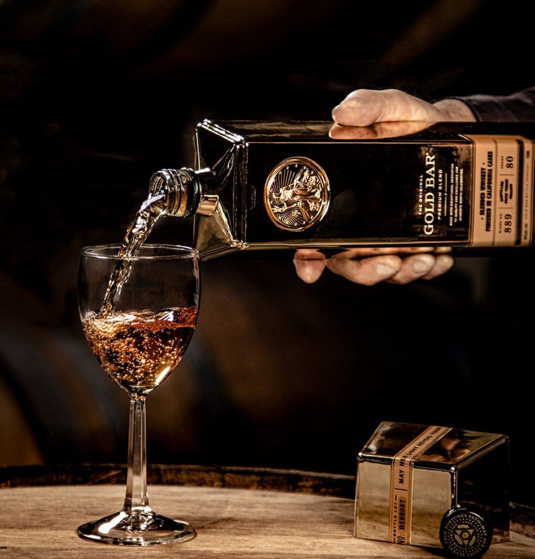 Pouring Gold Bar Original Premium Blended Whiskey into a glass, highlighting rich color and smooth texture.