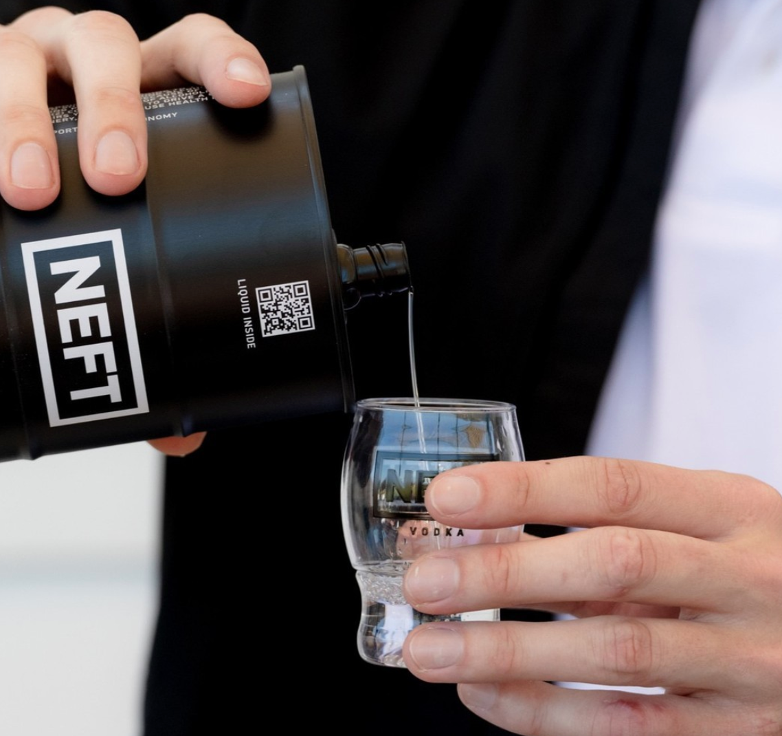 Pouring NEFT Black Barrel Australian Vodka from a canister into a shot glass.