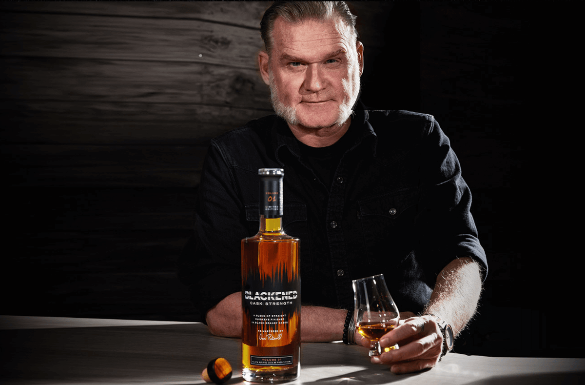 Blackened Volume 1 Cask Strength Blended Whiskey displayed with a glass, showcasing its rich color and bold flavor.