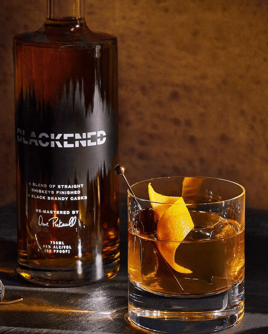 Blackened American Whiskey bottle with a glass, showcasing a blend of straight whiskeys finished in black brandy casks.