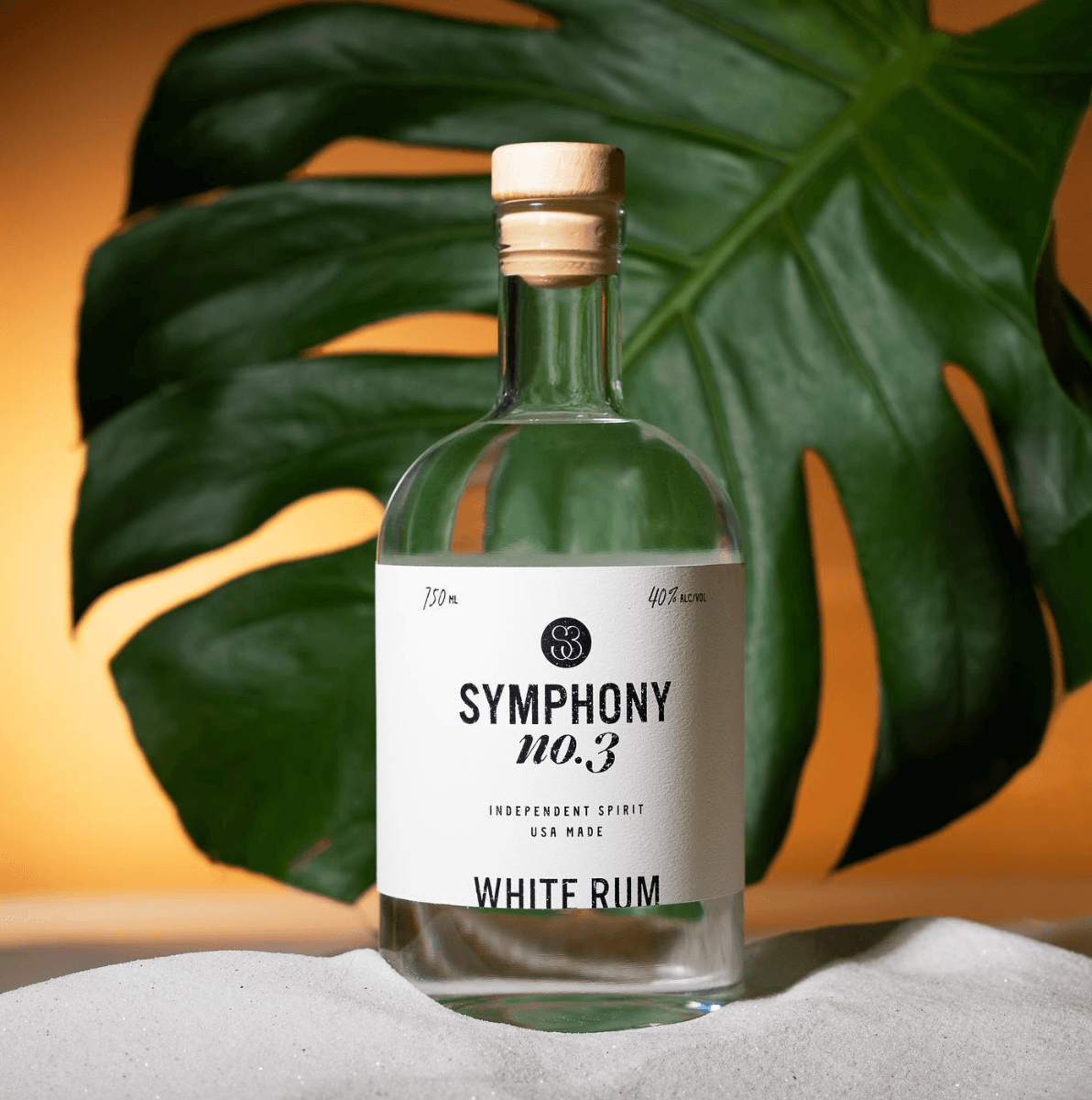 Symphony No.3 white rum bottle against a tropical leaf background, showcasing its elegant design and clarity.