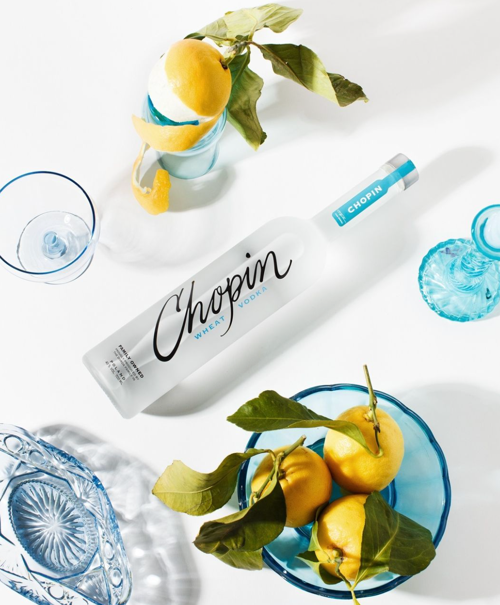 Chopin Wheat Vodka bottle surrounded by lemons and stylish glassware, showcasing its refreshing summer appeal.