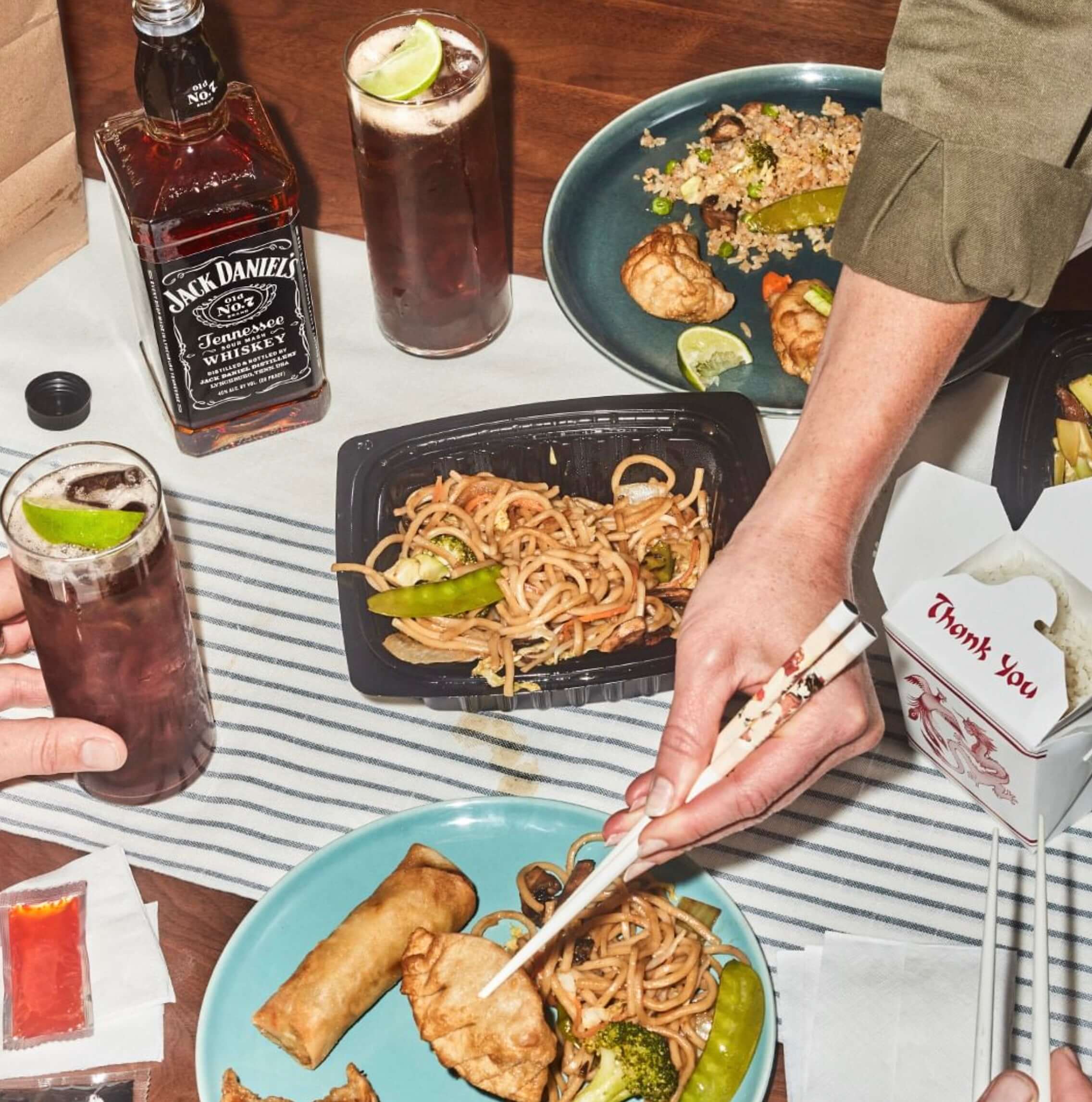 Jack Daniel's Tennessee Whiskey bottle next to Asian cuisine on a table, showcasing a casual dining experience.