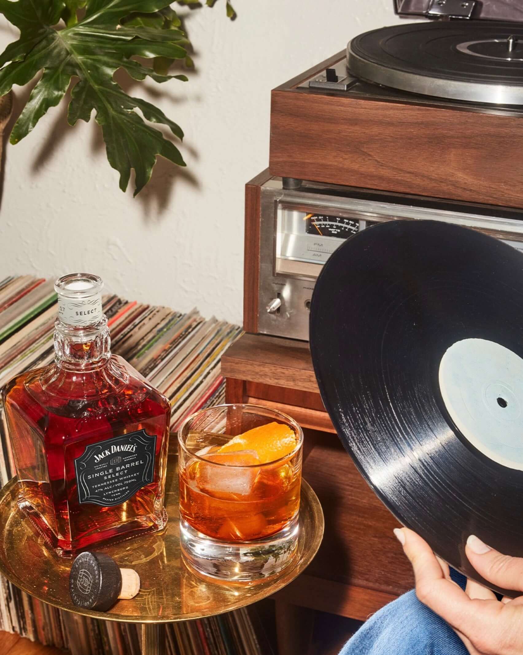 Jack Daniel's Single Barrel Select whiskey beside a vintage record player and glass of whiskey with an orange twist.