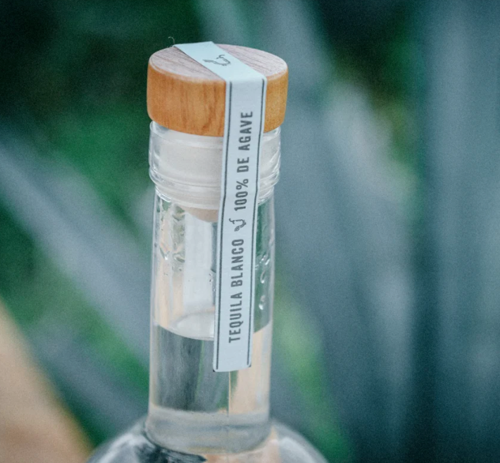 Close-up of Real Del Valle Blanco Tequila bottle cap with 100% de agave label, highlighting its quality and craftsmanship.