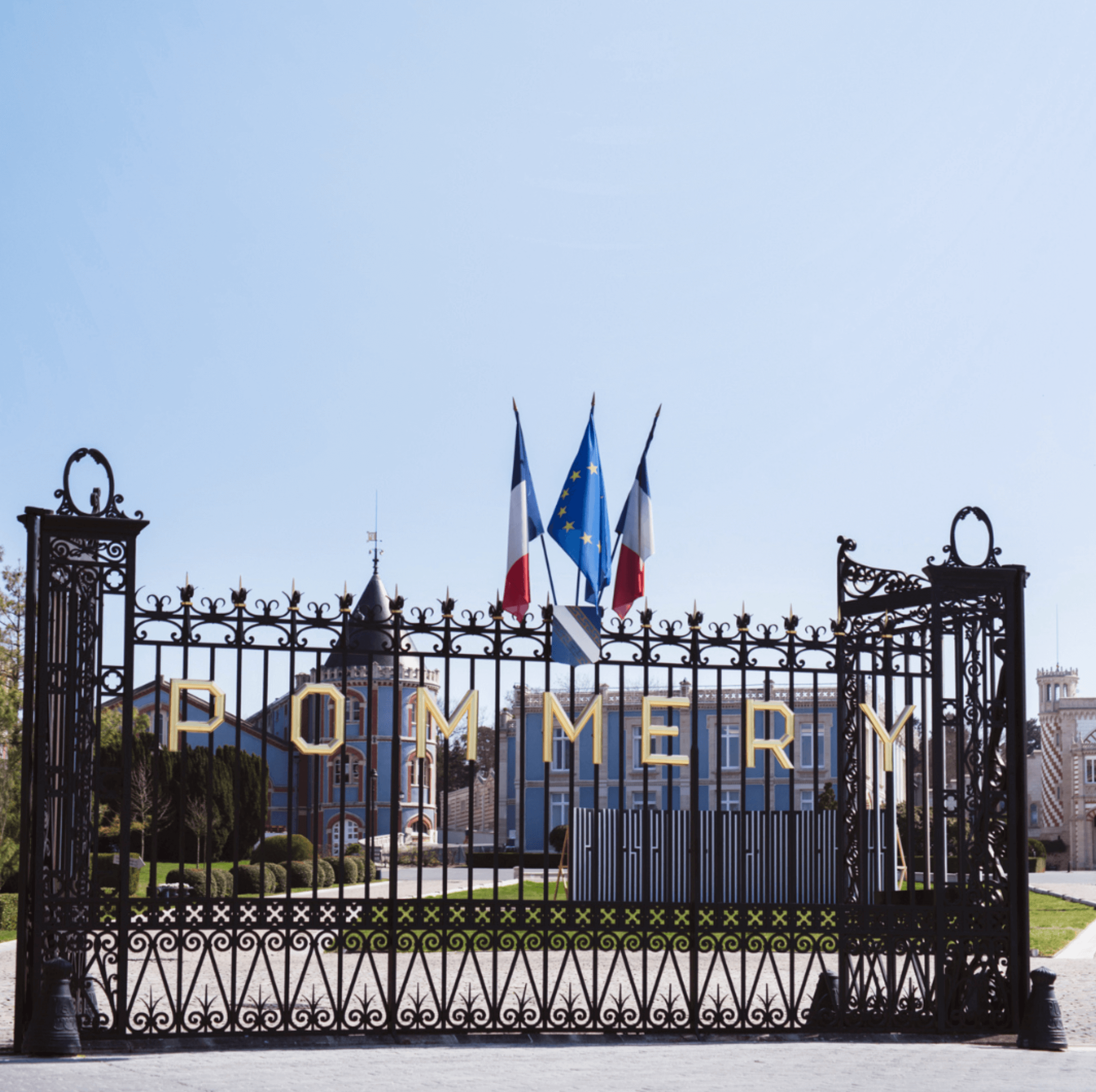 Pommery Champagne gate with French flags, showcasing the brand's historic estate and elegant architecture.