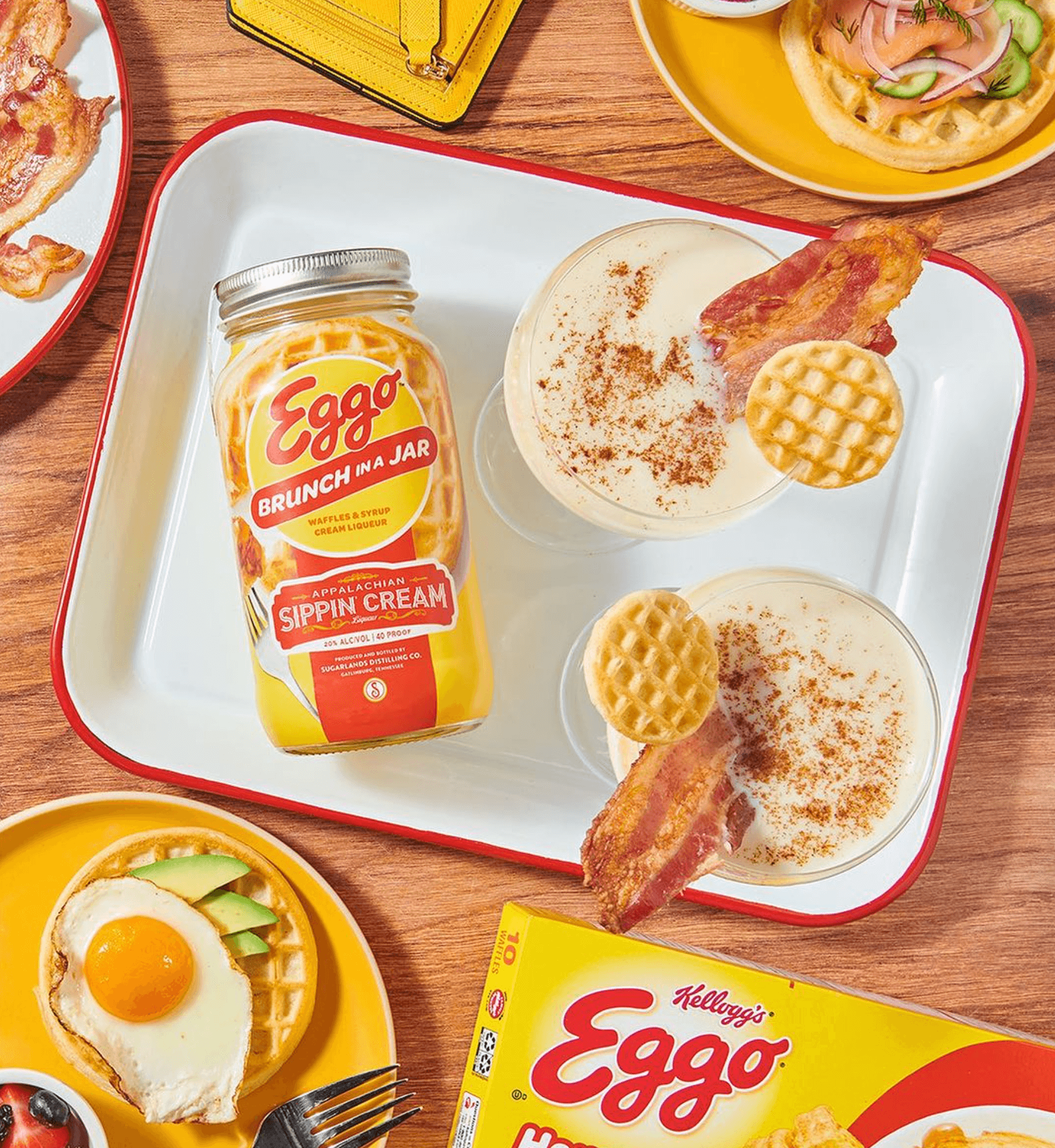 Eggo Nog Appalachian Sipping Cream in jar with glasses of eggnog, waffles, and breakfast items on a wooden table.