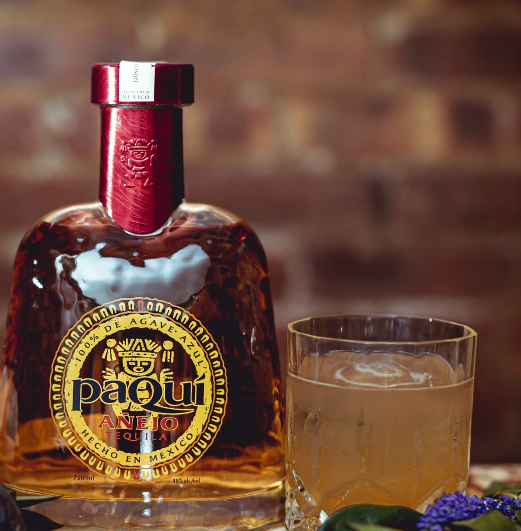 PaQuí Añejo Tequila bottle with a glass of cocktail, showcasing its artisanal craftsmanship and unique aroma.