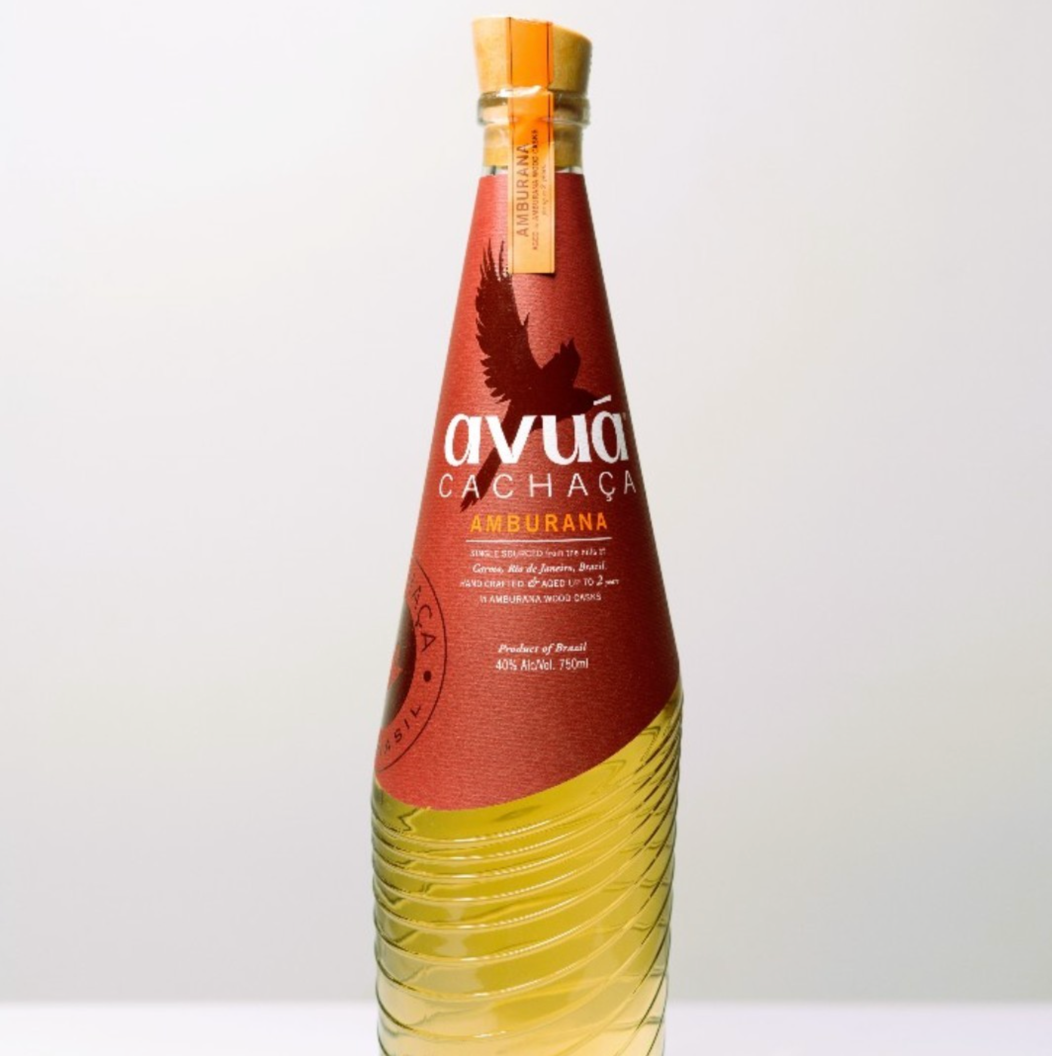 Bottle of Avuá Amburana Cachaça showcasing its unique design and rich amber color, aged in Amburana wood.