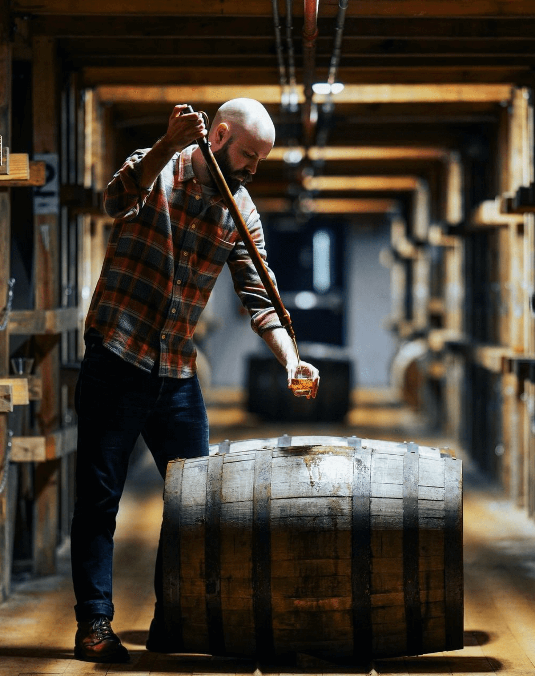 Master Distiller Owen Martin sampling bourbon from a barrel in a distillery.
