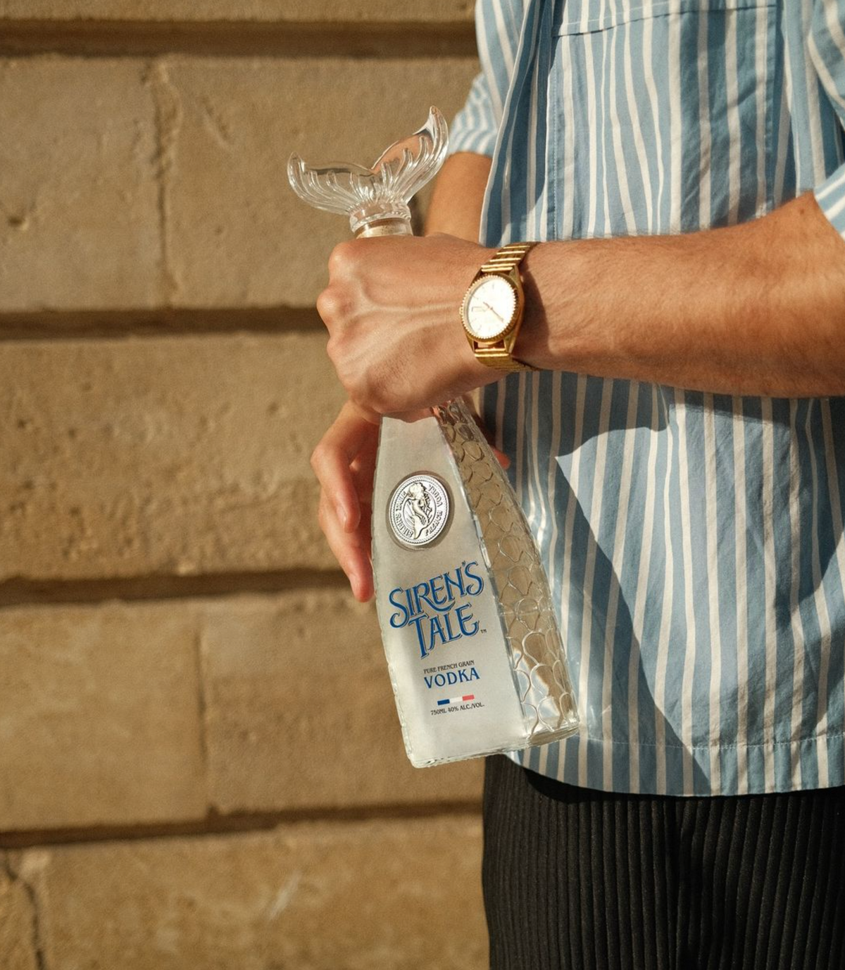 Siren's Tale French Vodka in a limited edition tail bottle held by a person wearing a stylish outfit.