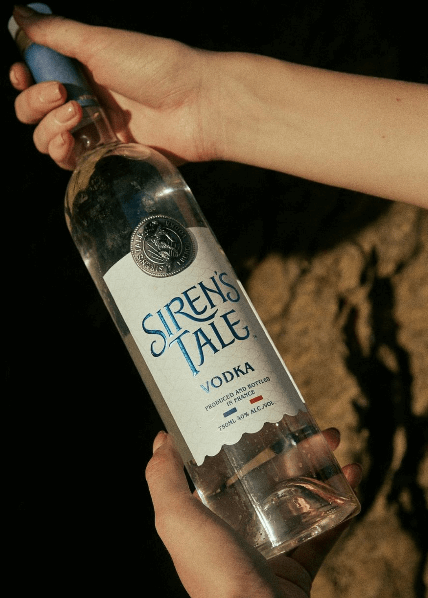 Siren's Tale Vodka bottle showcasing its elegant design and premium quality, held outdoors.