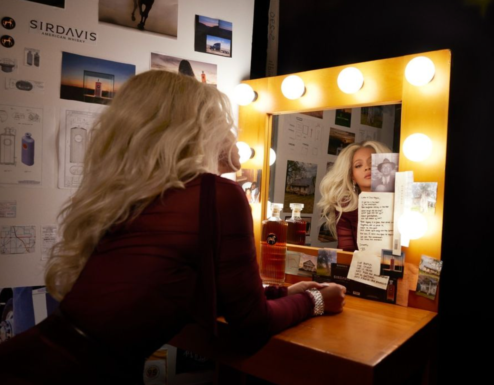 Beyoncé admiring SirDavis American whisky in front of a vanity mirror, surrounded by creative inspiration.