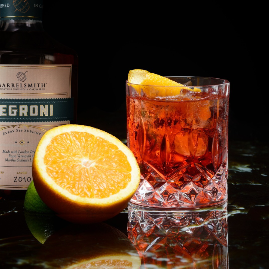 Barrelsmith Negroni cocktail featuring London Dry Gin, Rosso Vermouth, and an orange slice on a dark background.