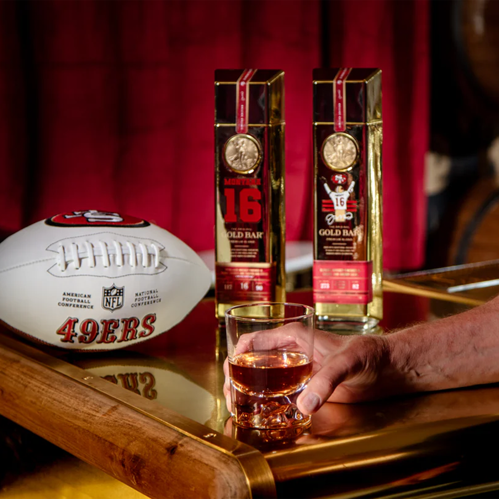 Gold Bar Joe Montana Blend whiskey with a football and glass on a wooden table, celebrating Super Bowl XXIV.
