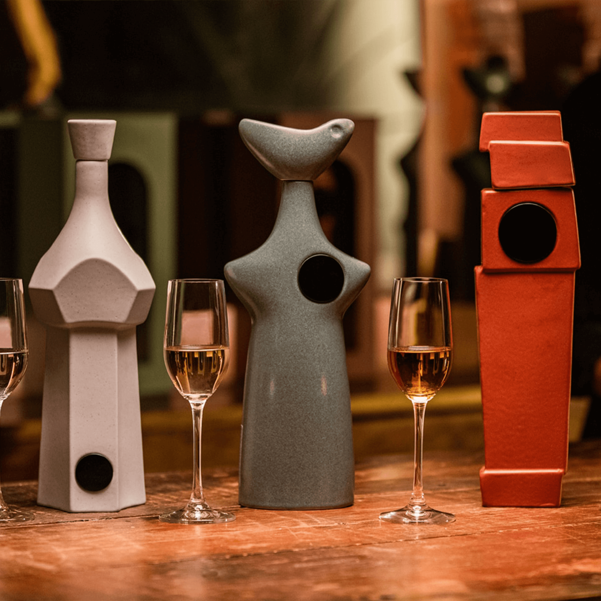Casa Obsidiana Añejo Tequila bottles in artistic shapes with glasses, showcasing Mexican culture and craftsmanship.