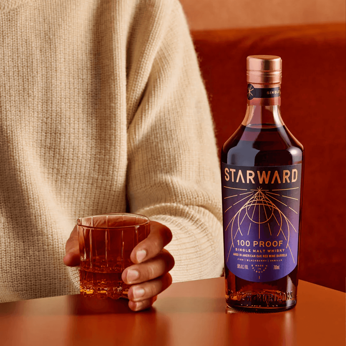 Starward 100 Proof Single Malt Whisky bottle beside a glass, showcasing its rich amber color and elegant packaging.