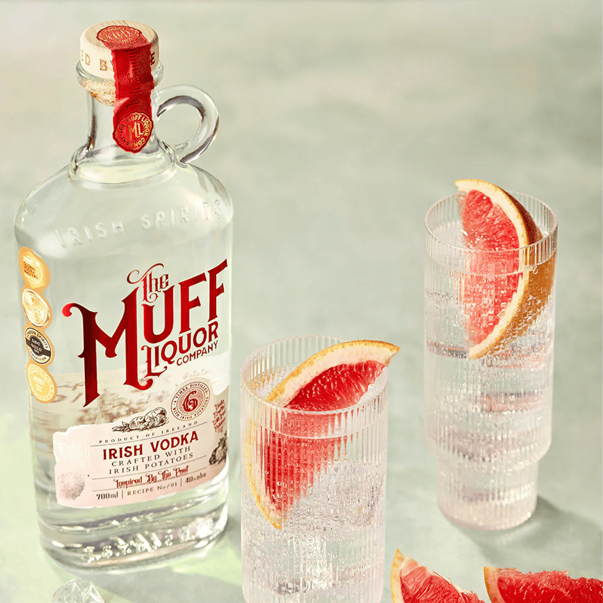 The Muff Liquor Irish Potato Vodka bottle with two glasses of vodka garnished with grapefruit slices.